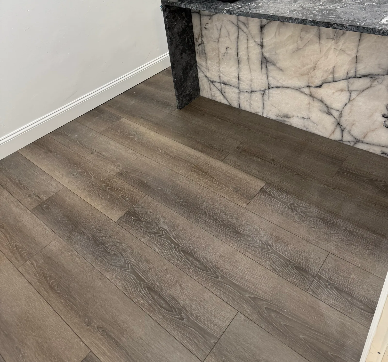 Style SPC Nova 6.5mm grey oak luxury vinyl plank running up to a marble waterfall counter in a Southwest Florida install