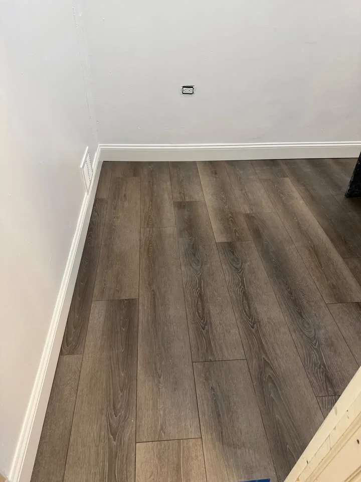 Greige wide-plank luxury vinyl flooring with tight seams and a clean baseboard line