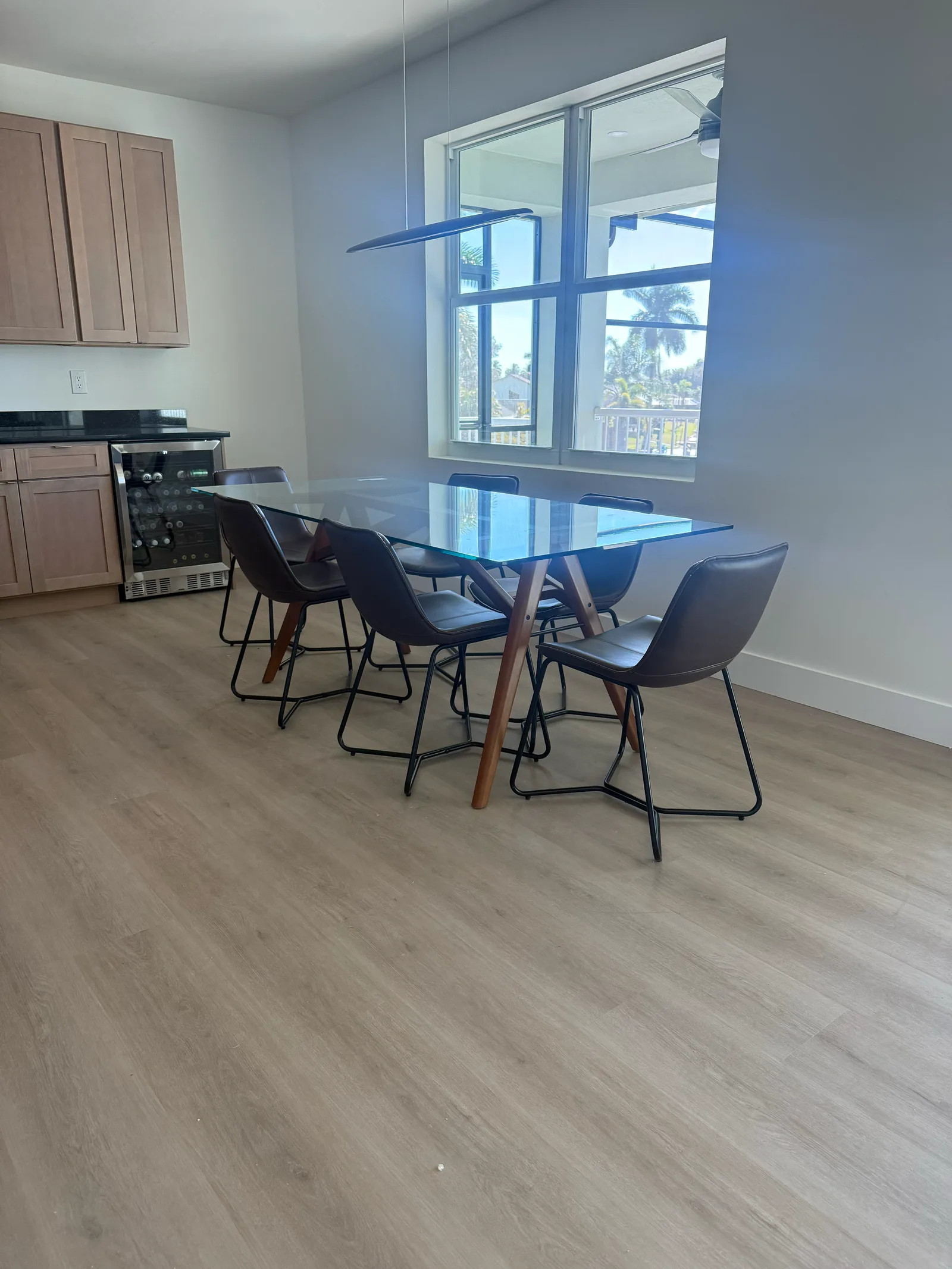 Light oak SPC vinyl plank flooring in a dining area with a glass table and black chairs, Cape Coral