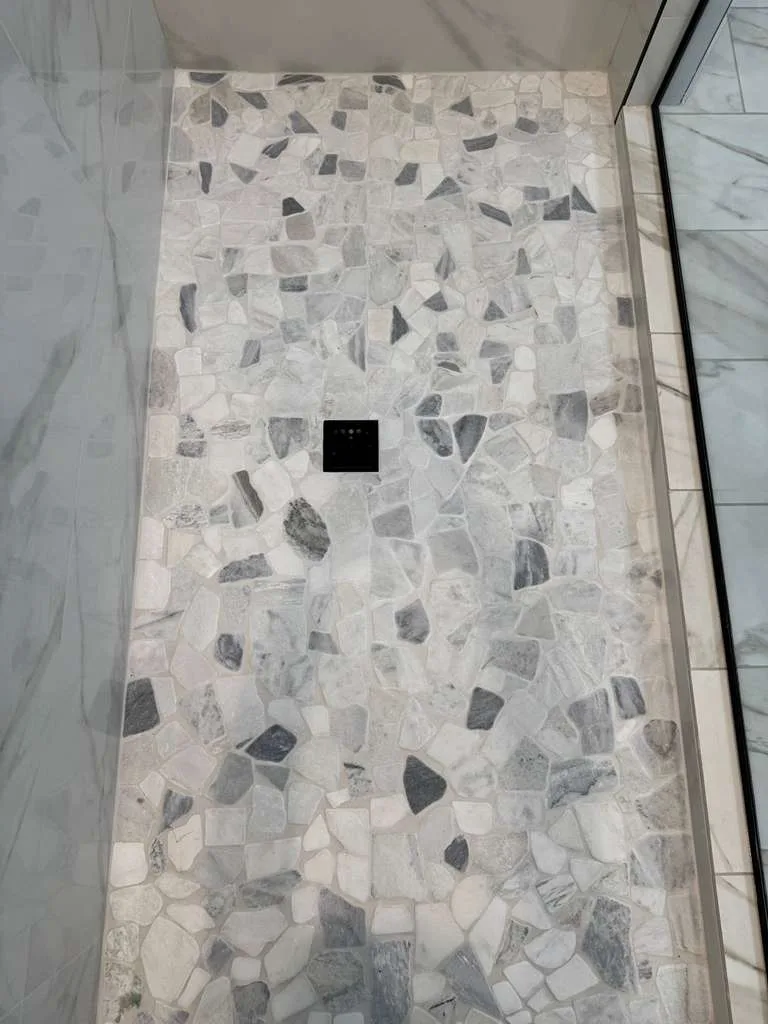 Pebble mosaic shower pan and tiled walls in a Southwest Florida bathroom