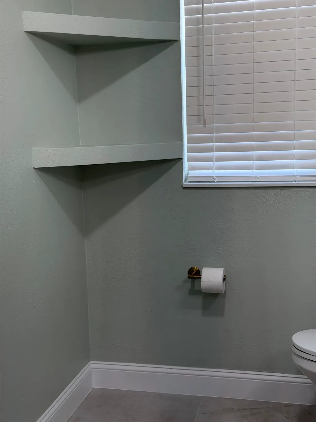 Floating shelves and tile floor in a remodeled powder room