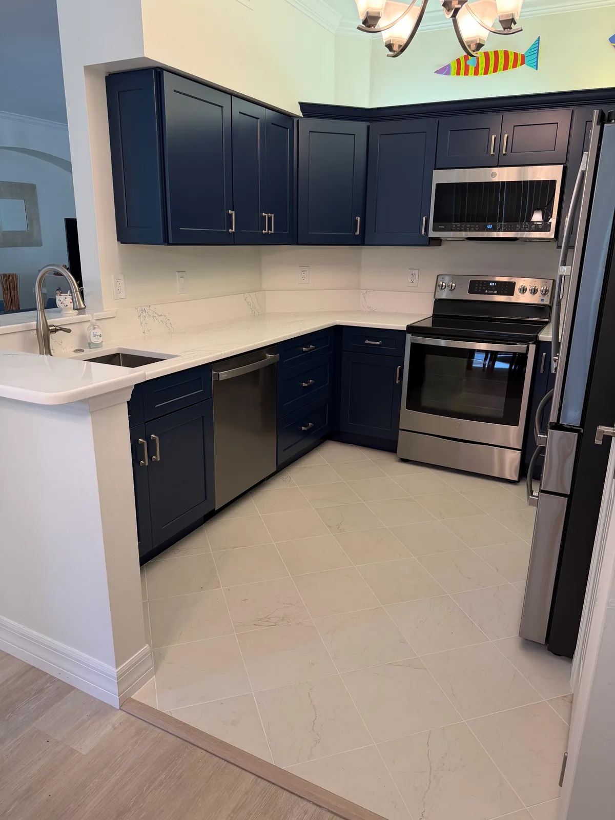 Navy kitchen peninsula in white quartz with a stainless dishwasher