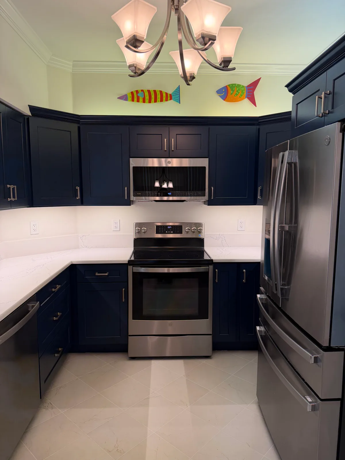Stainless range and microwave set into navy cabinetry with a quartz backsplash
