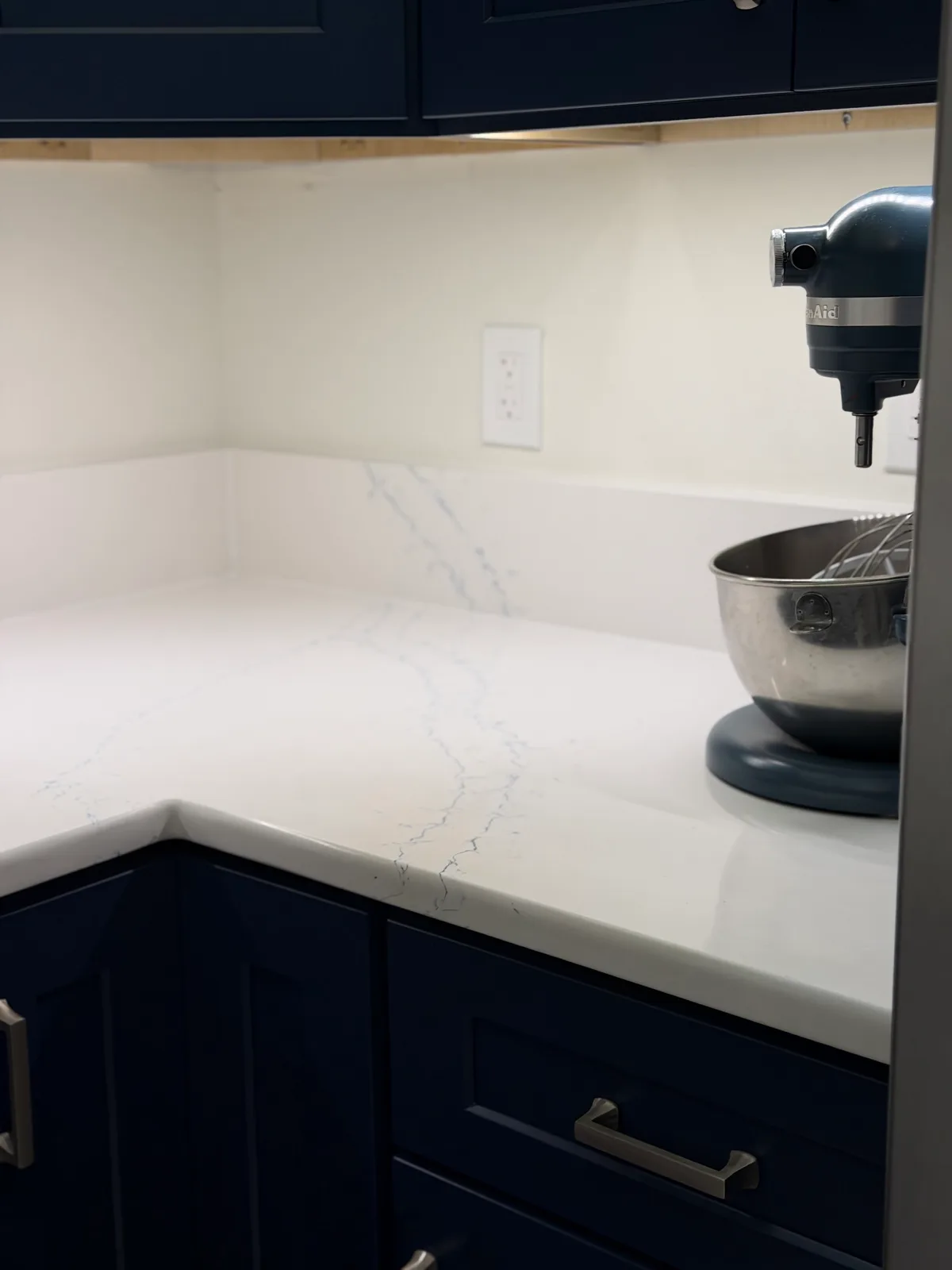 Quartz counter return over navy base cabinets with brushed nickel pulls