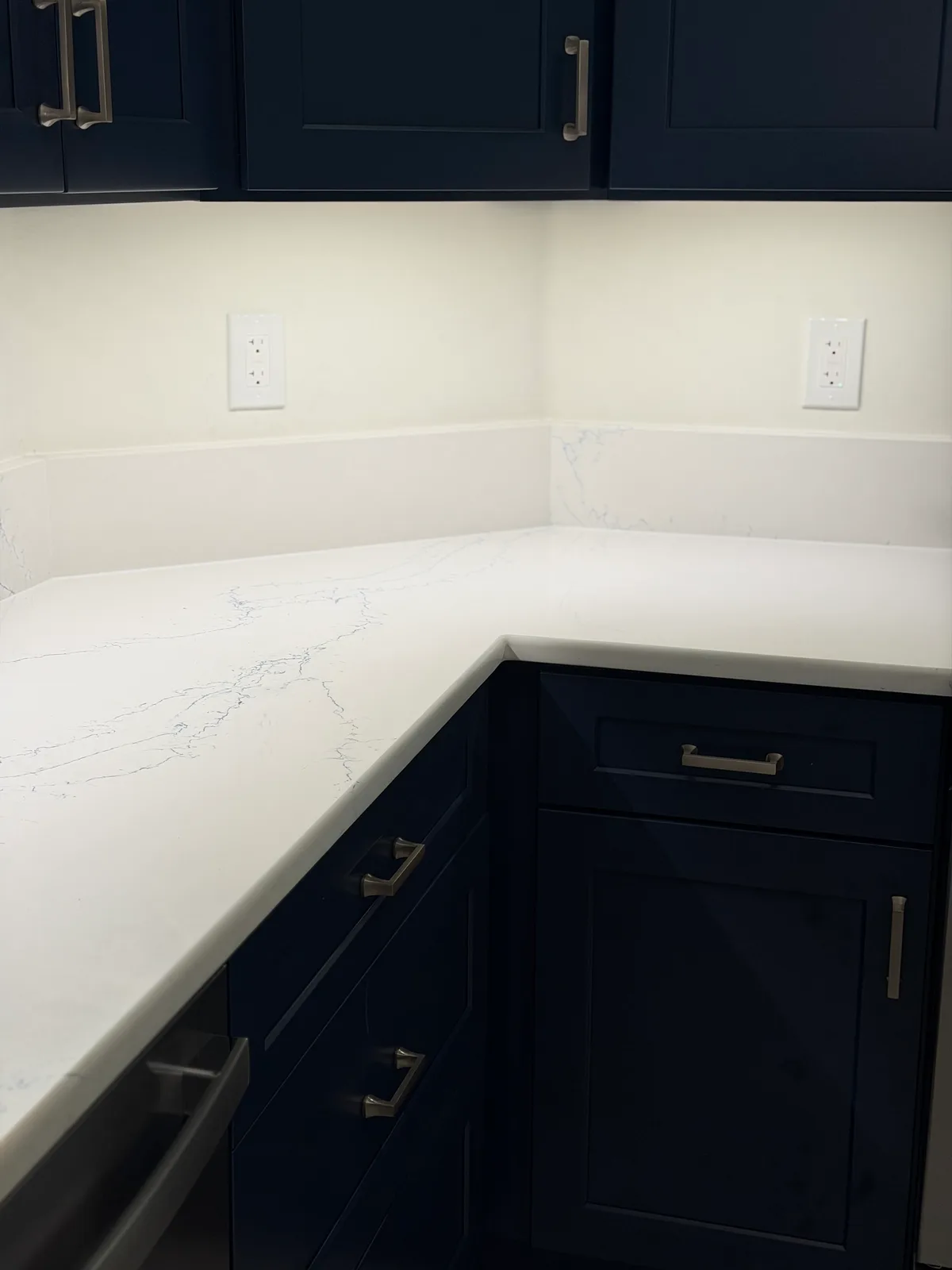 White quartz counter running the corner over navy shaker base cabinets