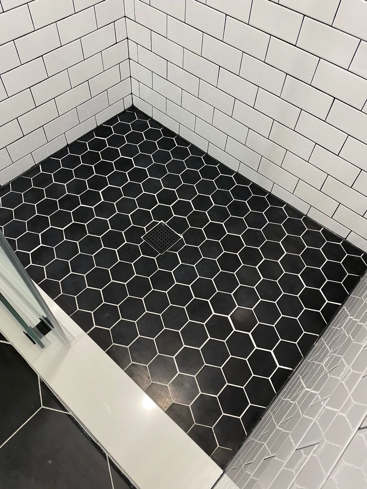 Black hexagon mosaic shower floor against white subway tile walls
