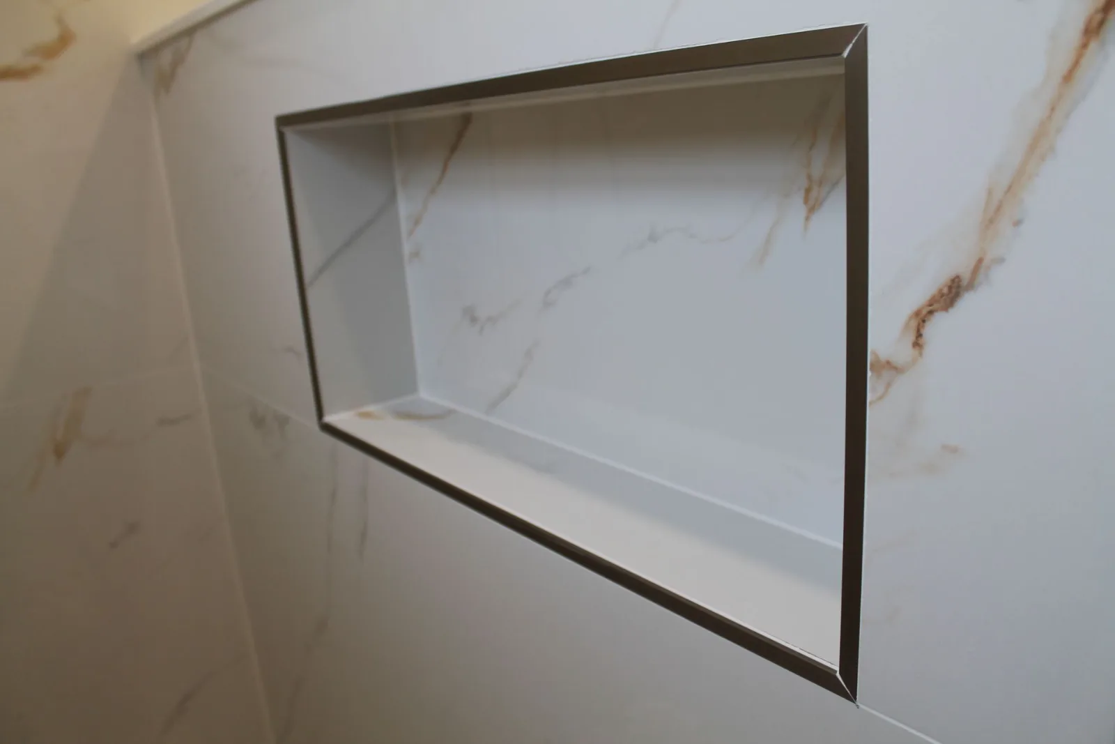 Calacatta-look shower niche trimmed in brushed nickel