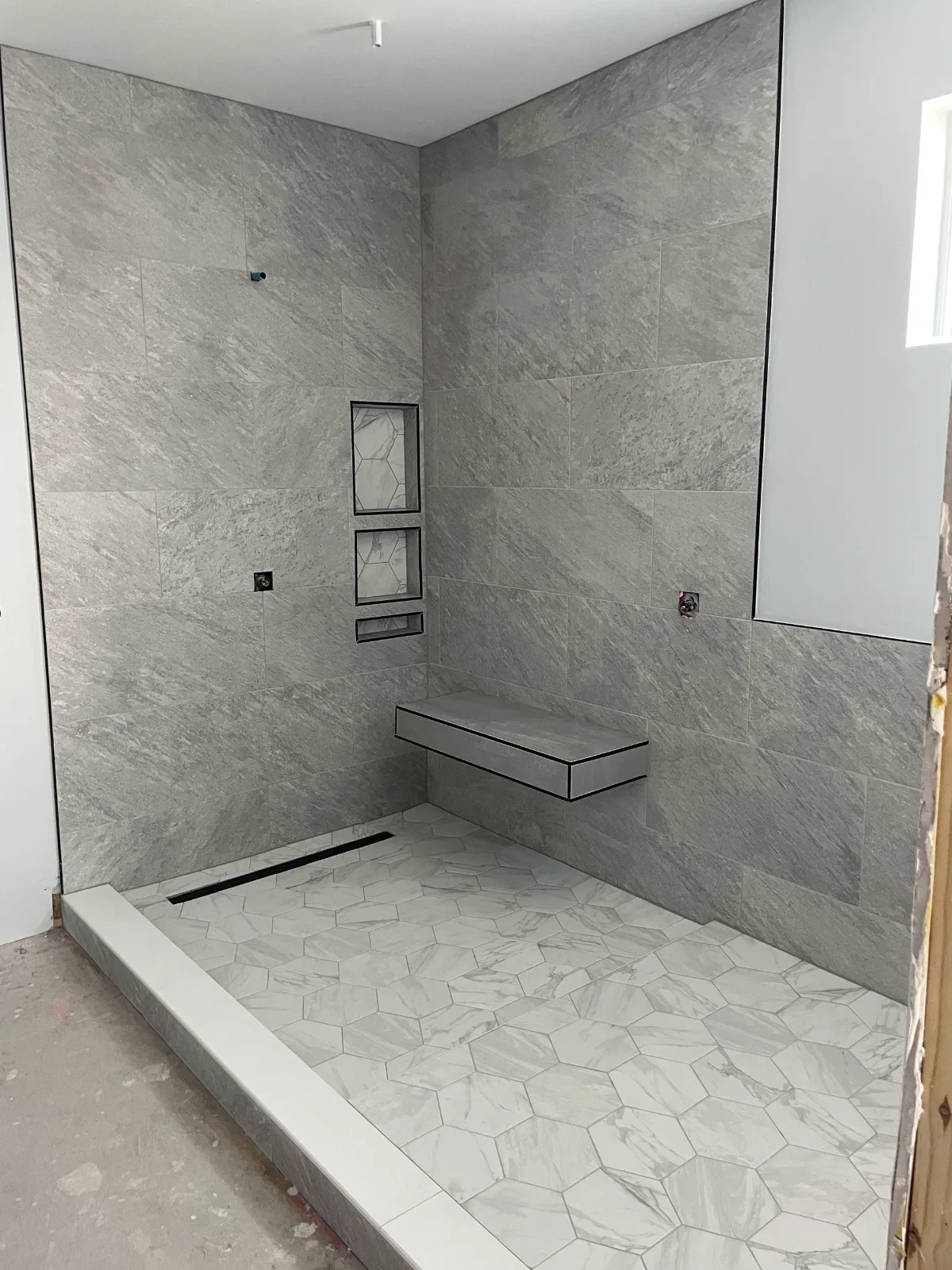 Curbless shower with linear drain and floating quartz bench in gray porcelain