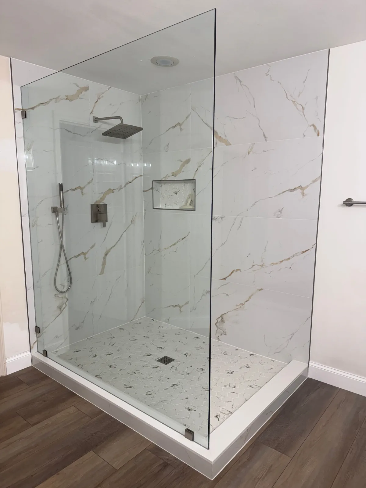 Frameless corner shower enclosure in calacatta-look porcelain tile