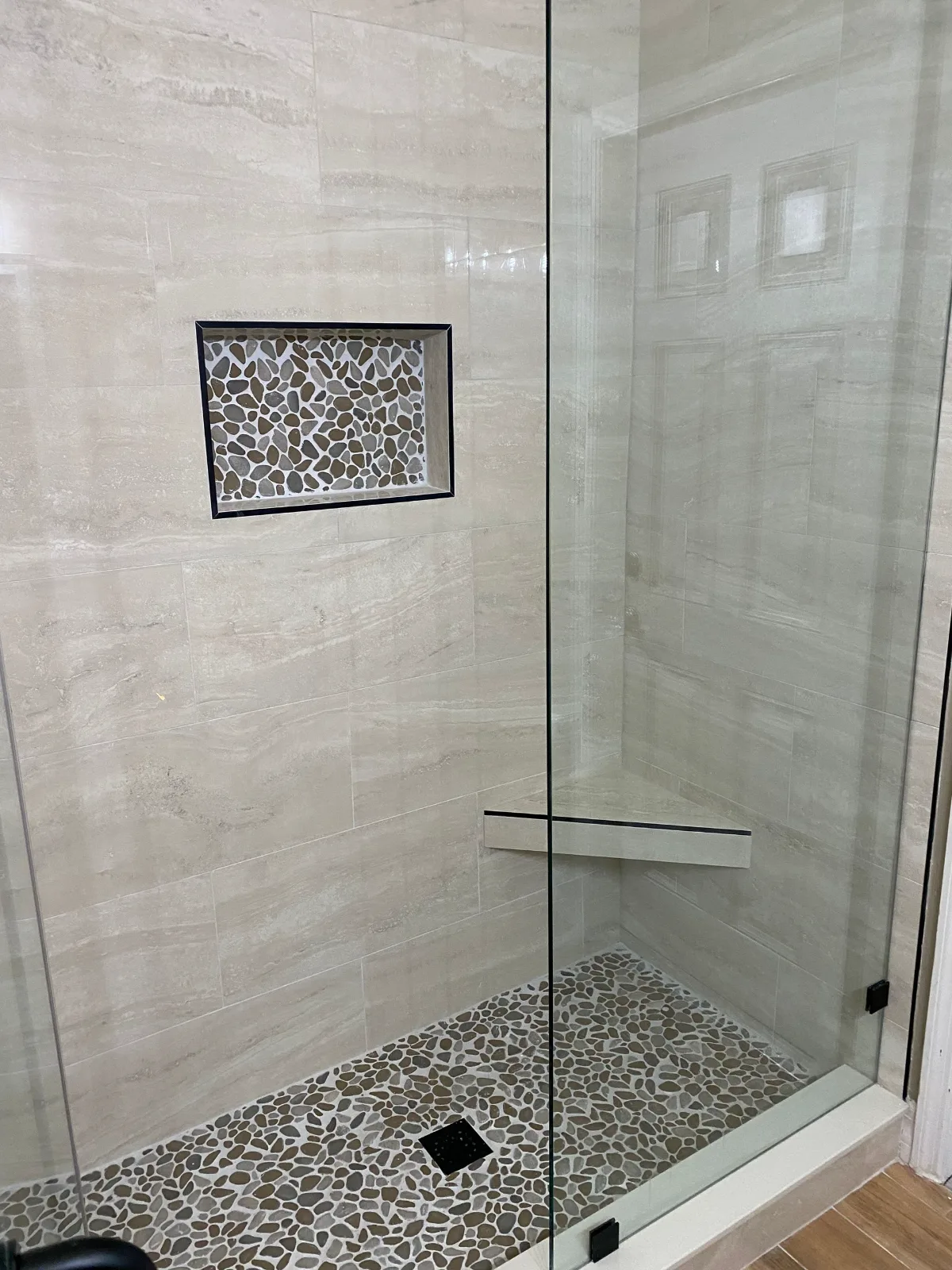 Frameless glass shower with recessed mosaic niche and linear tile walls