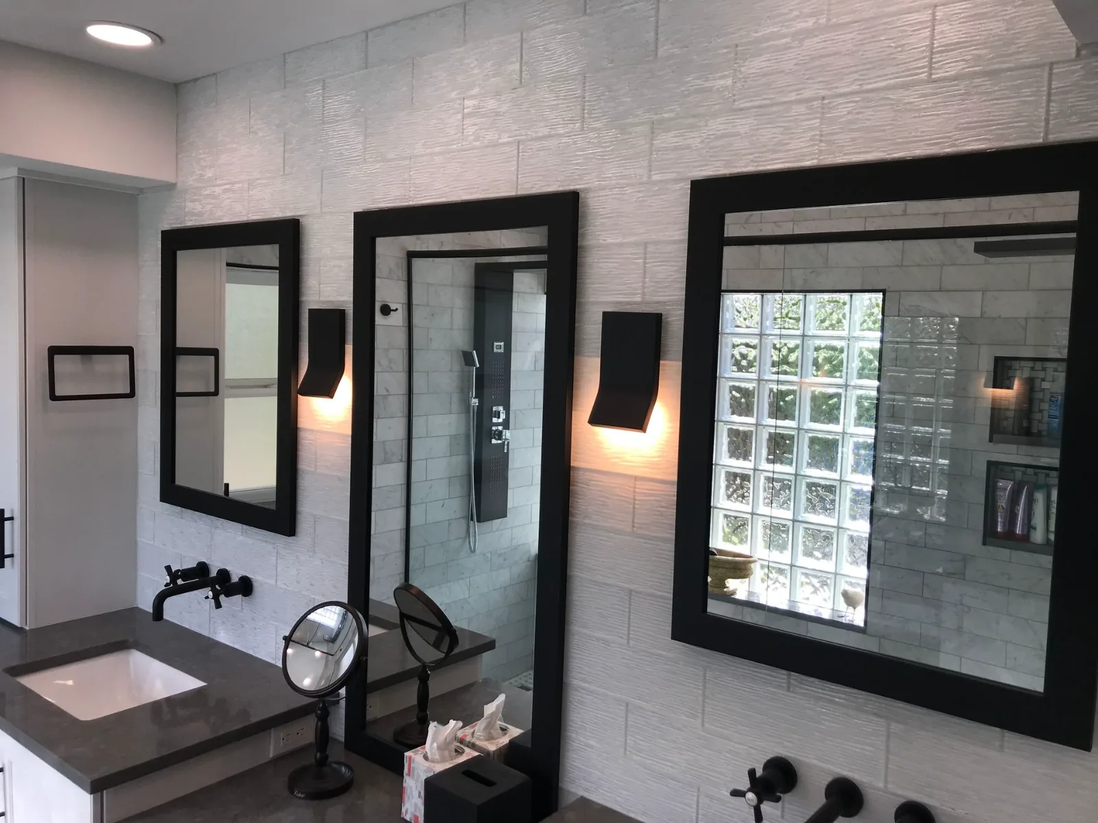 Glass block shower window with black framed mirrors and wall sconces