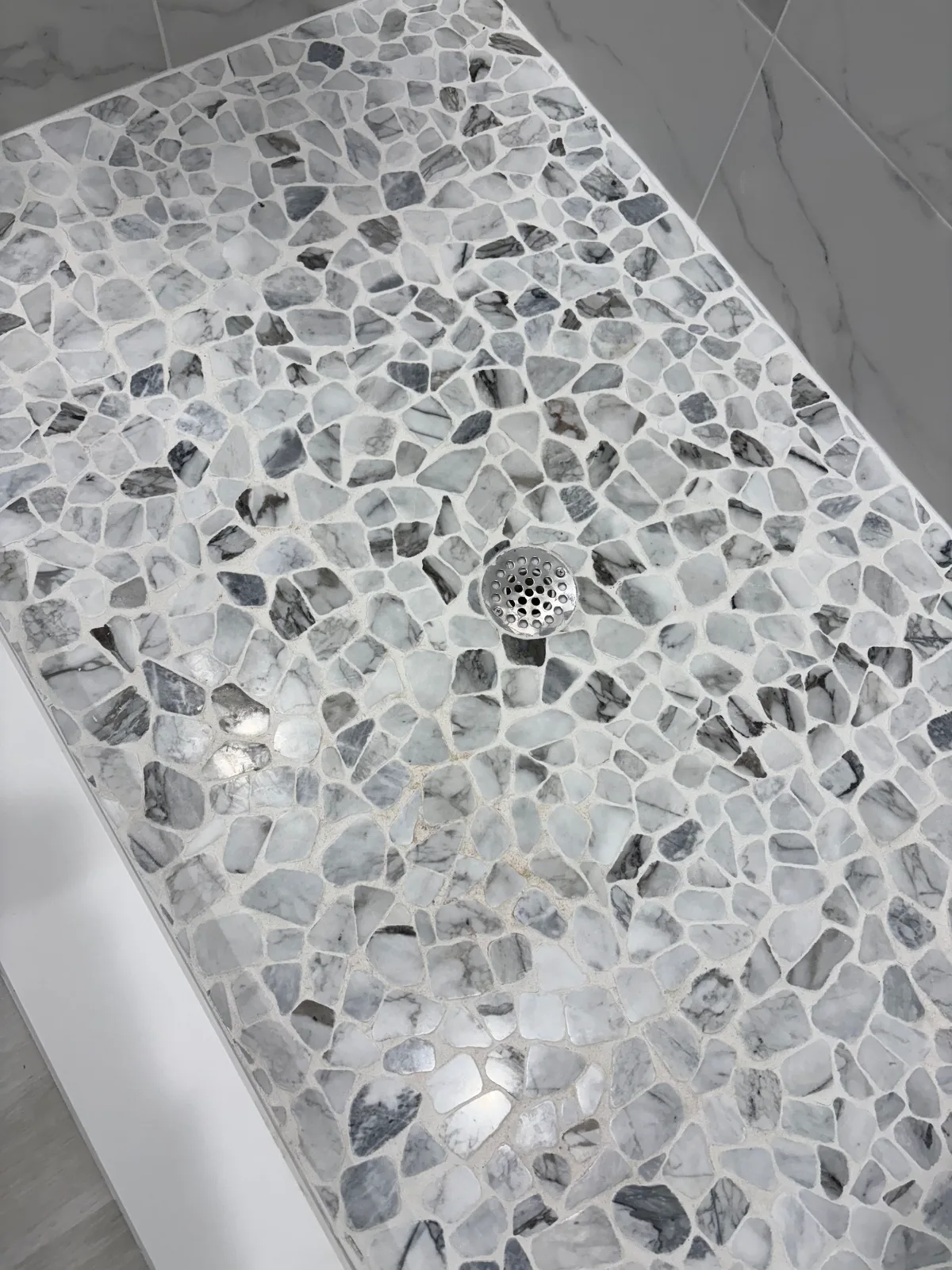 Gray pebble mosaic shower pan with clean grout lines