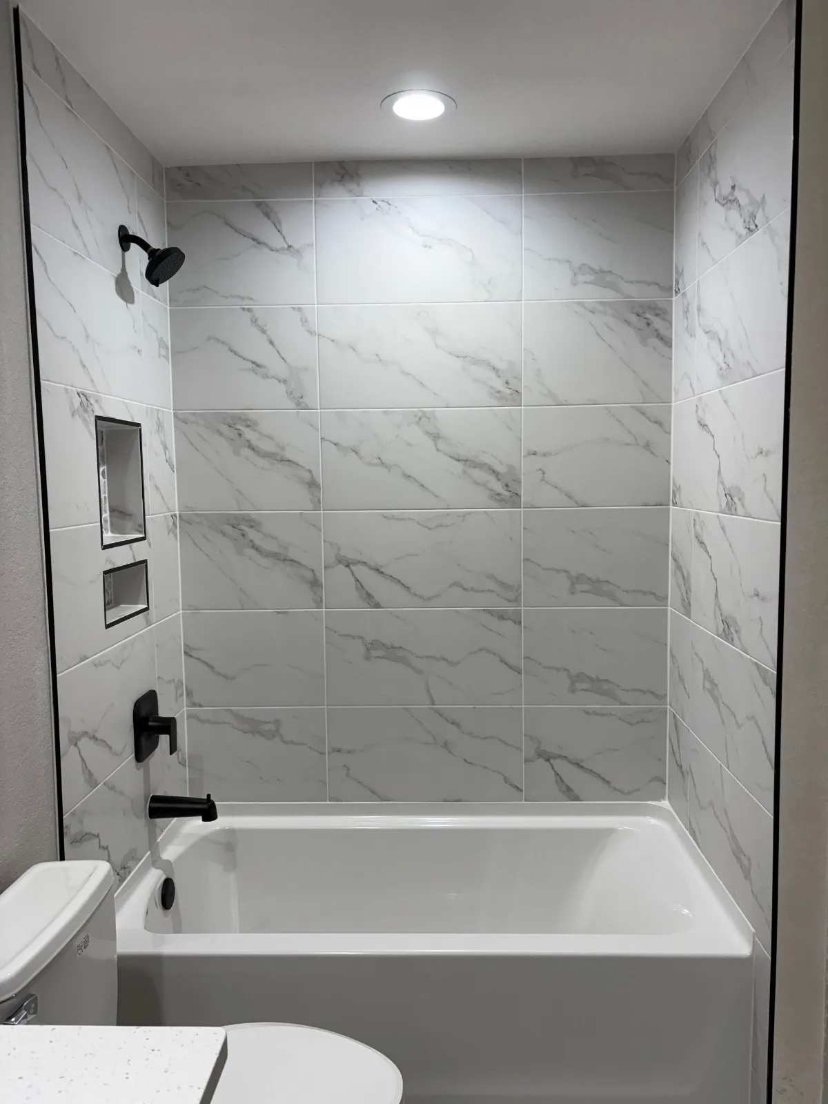 Marble-look tile tub surround with a recessed shampoo niche