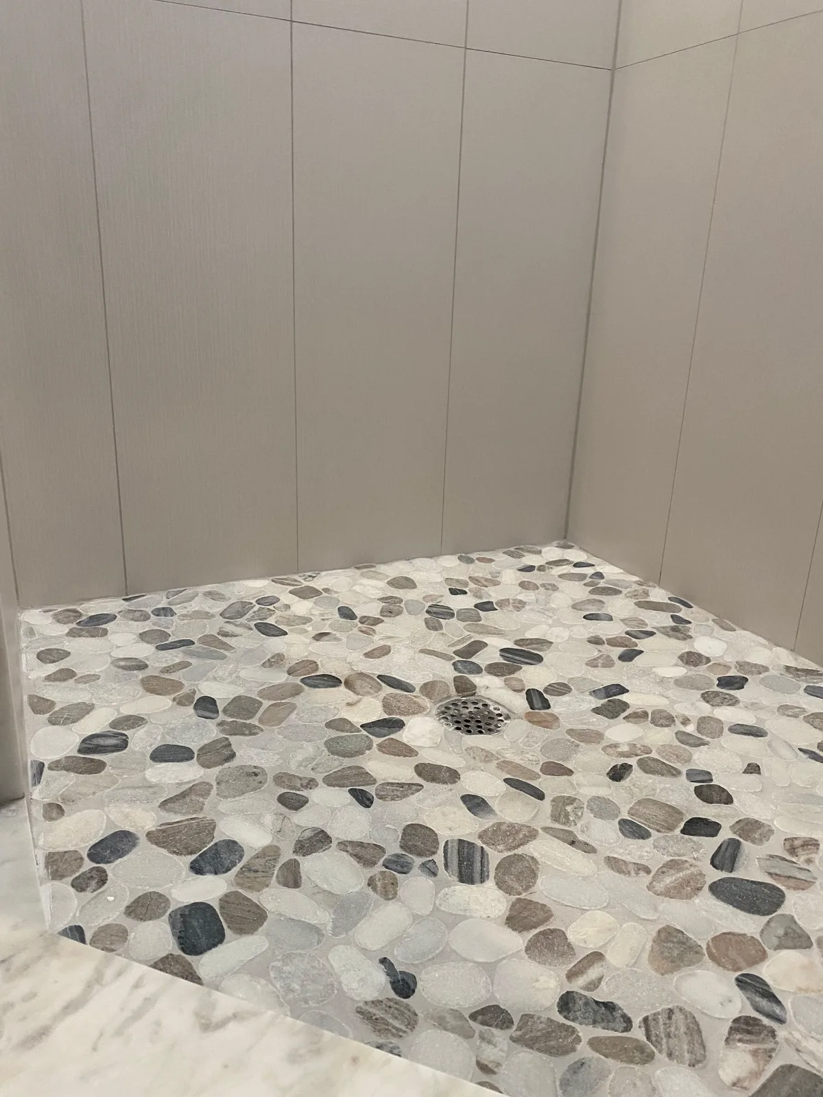 Pebble mosaic shower floor with large-format porcelain walls