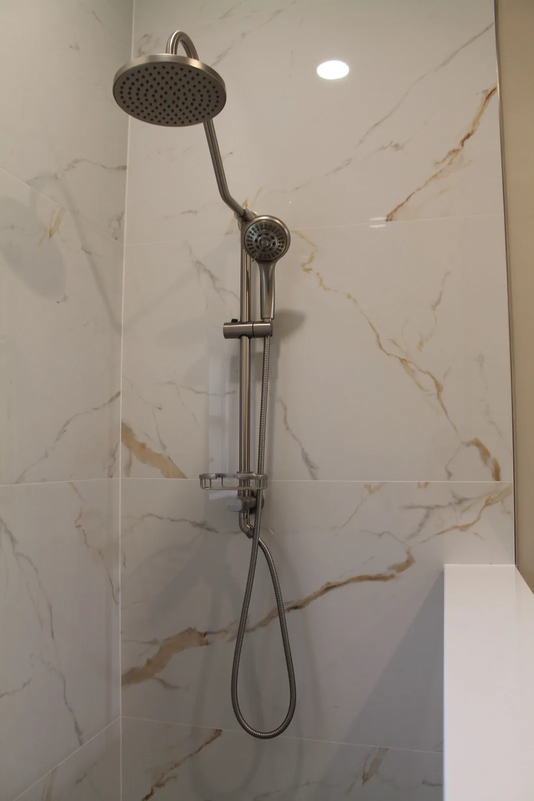Handheld shower on a slide bar against calacatta-look porcelain tile