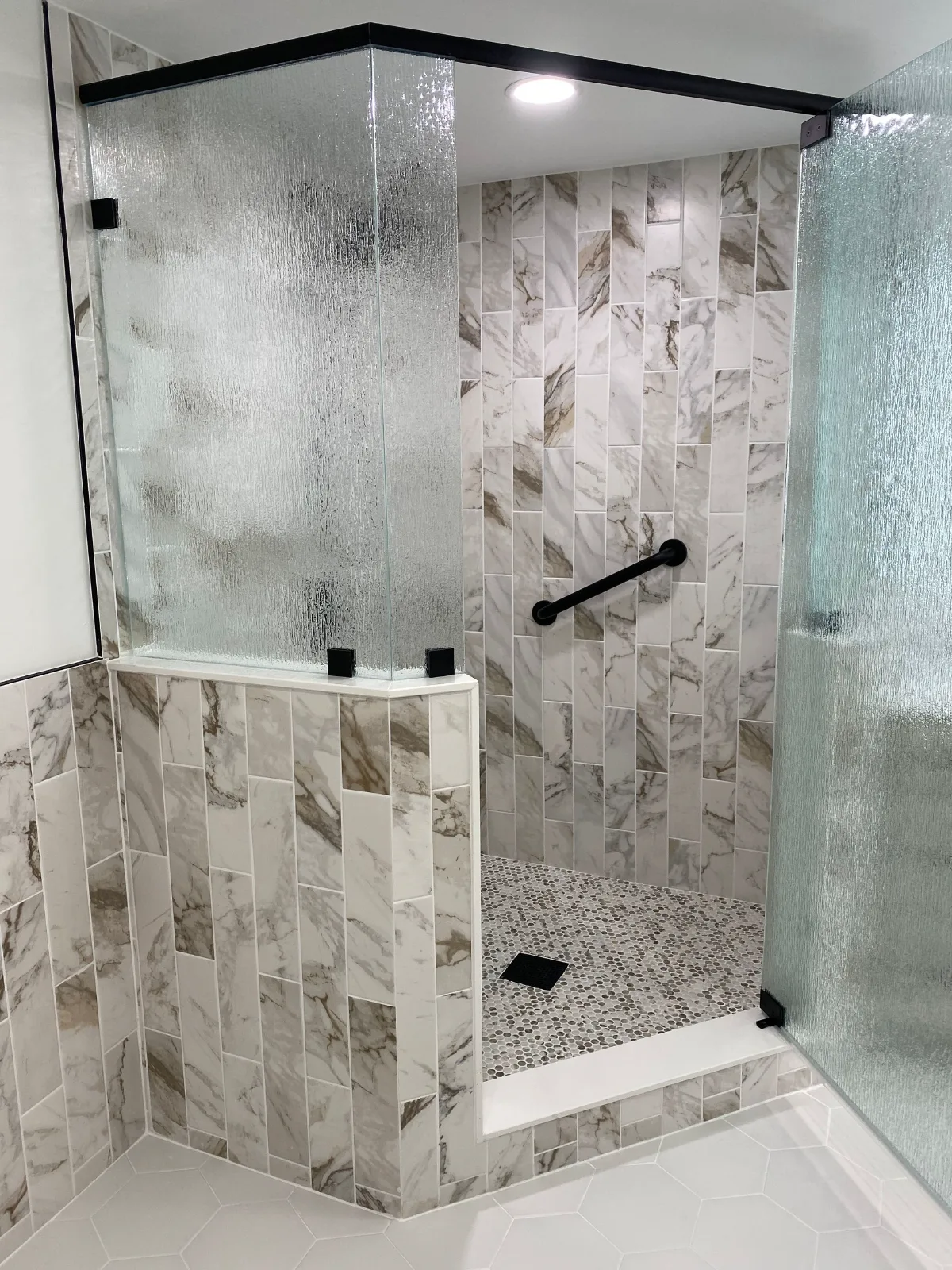 Stone-look tile shower behind a rain-glass enclosure