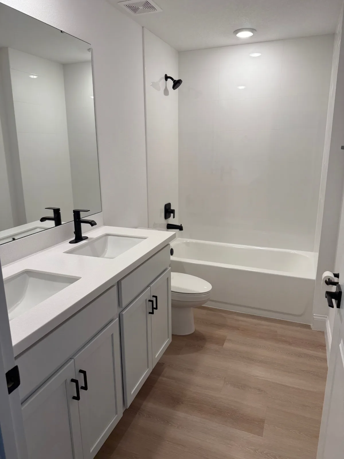 Tub shower combo beside a double vanity with matte black fixtures