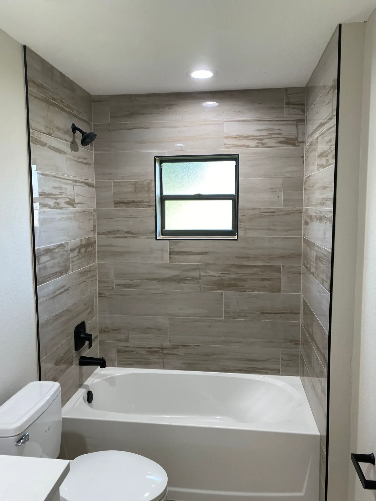 Tub and shower combination in wood-look tile with a shower window