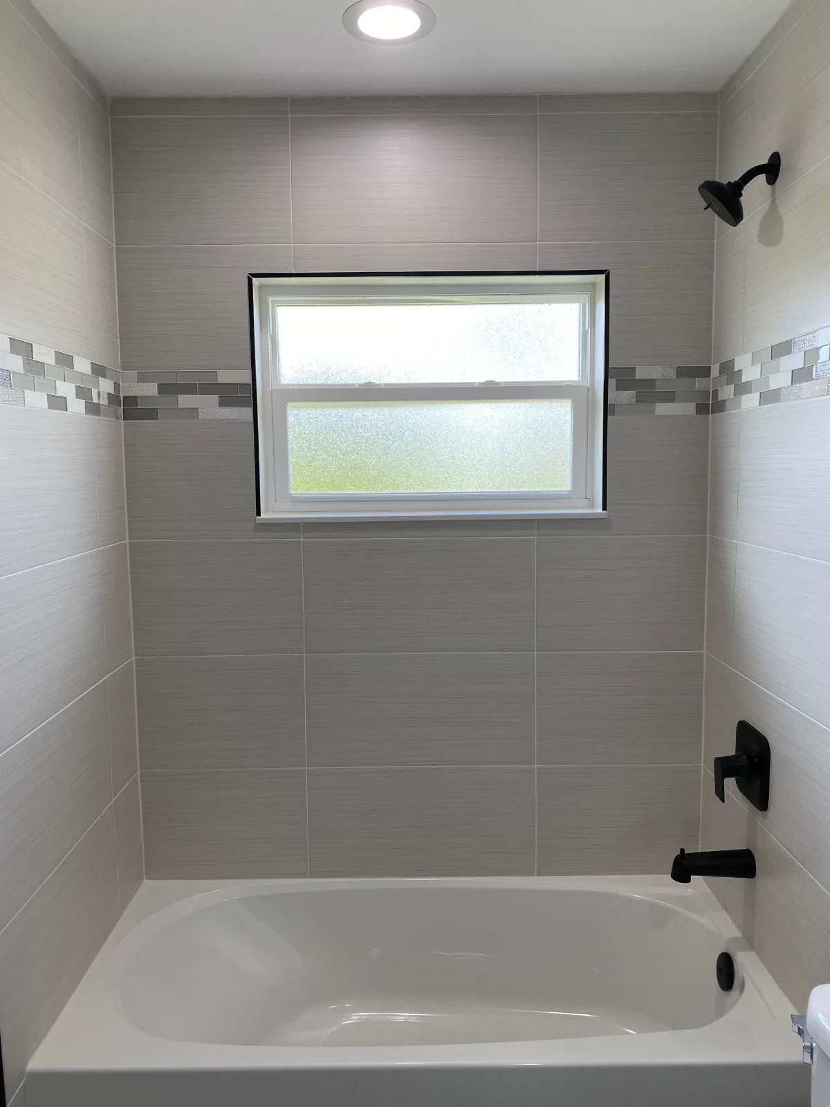 Tile tub surround with mosaic accent band and matte black fixtures