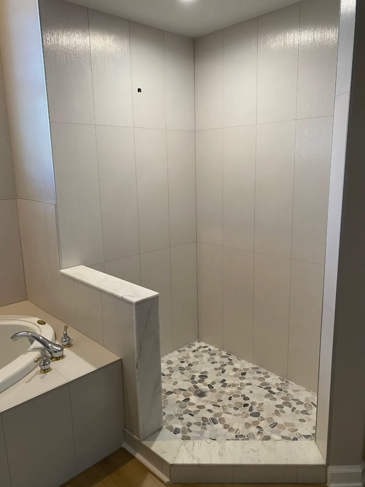 Walk-in shower with pebble floor and built-in corner bench