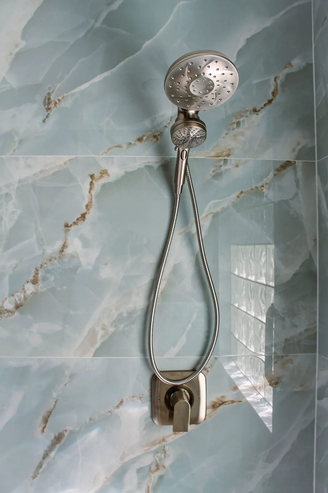 Brushed nickel handheld sprayer on blue onyx-look porcelain tile