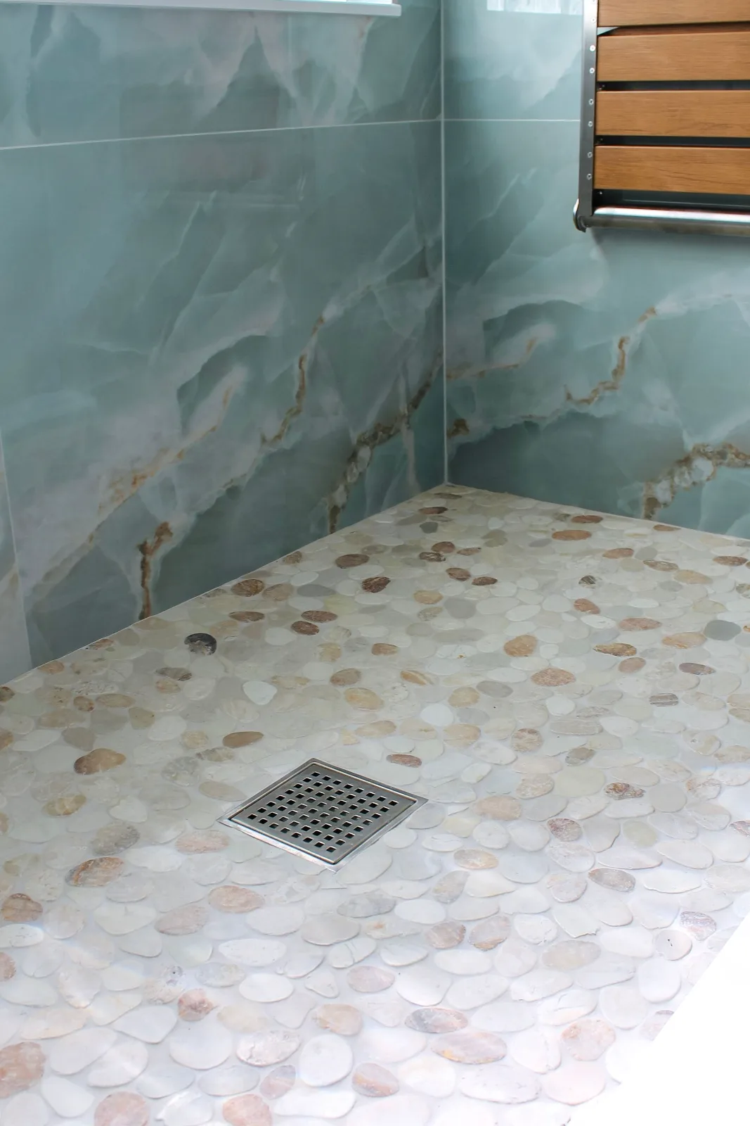 Pebble mosaic shower pan with a stainless square center drain