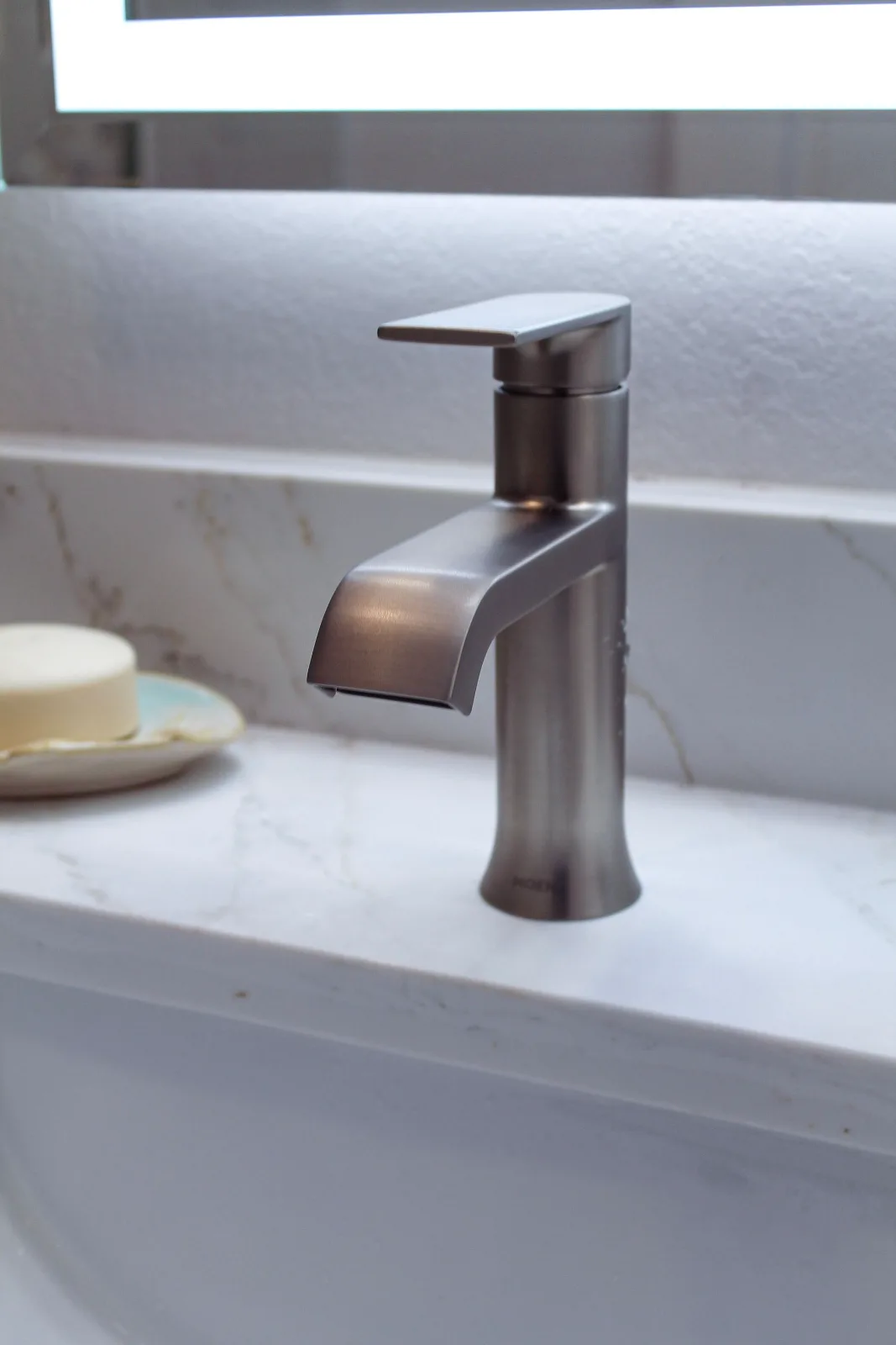 Single-handle brushed nickel faucet on a white quartz vanity top