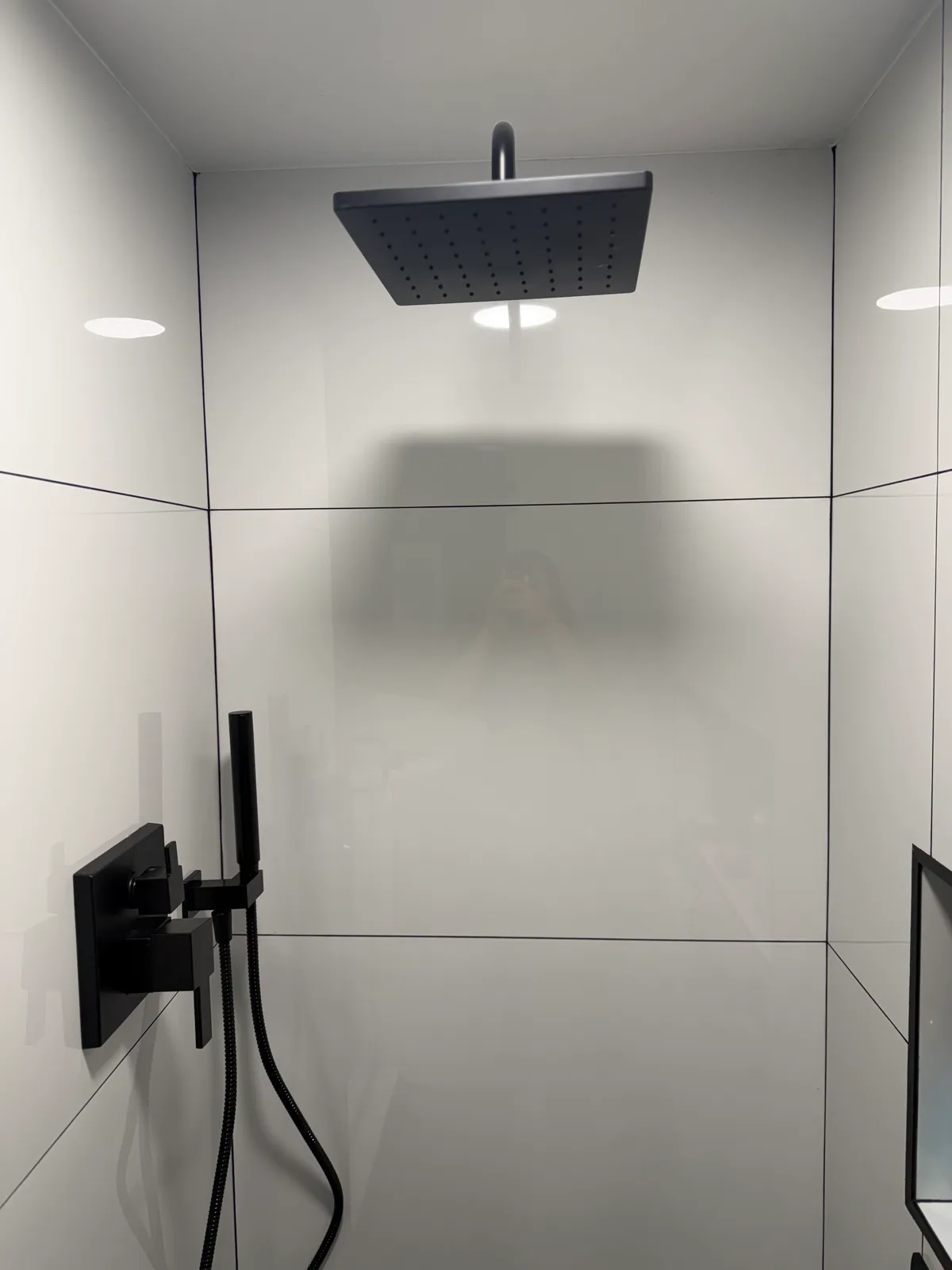 Matte black square rain shower head on large-format white tile, Naples
