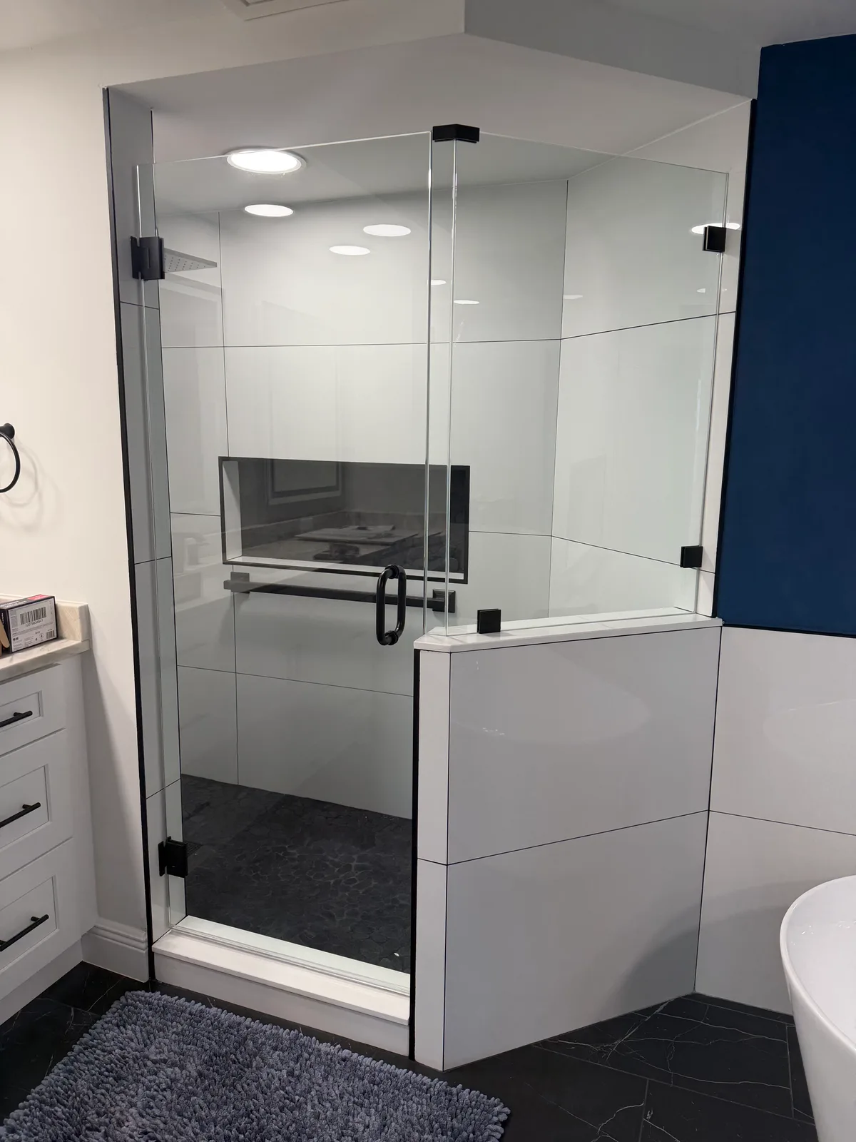 Frameless glass walk-in shower with a tiled half wall and built-in bench, Naples
