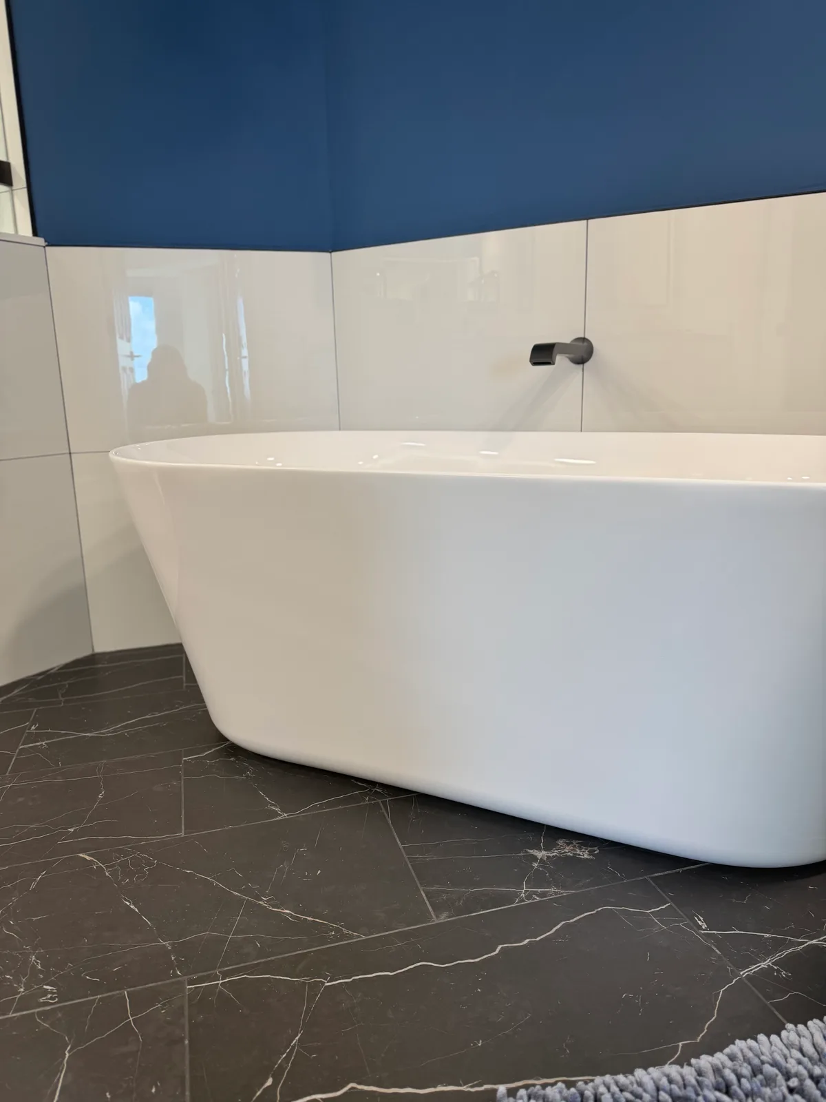 Freestanding soaking tub on black marble-look porcelain floor tile, Naples