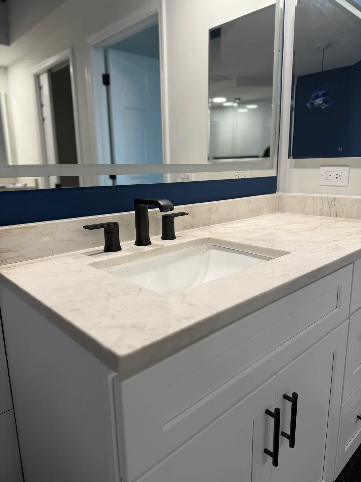 Veined quartz vanity top with an undermount sink and matte black widespread faucet