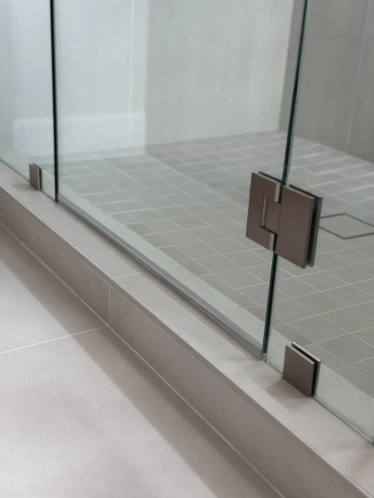 Frameless glass shower panel with brushed nickel hardware