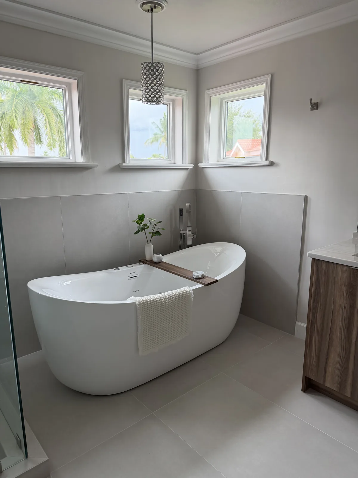Freestanding tub in a window corner against greige large-format tile