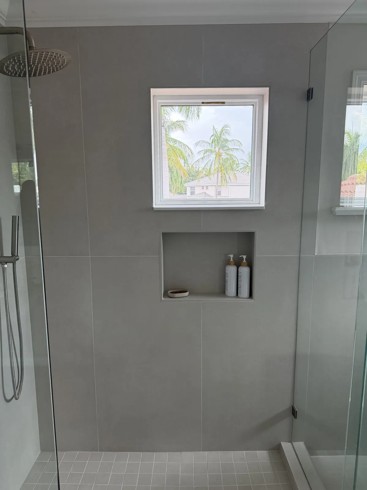Shower niche beside a window in greige large-format tile, Fort Myers
