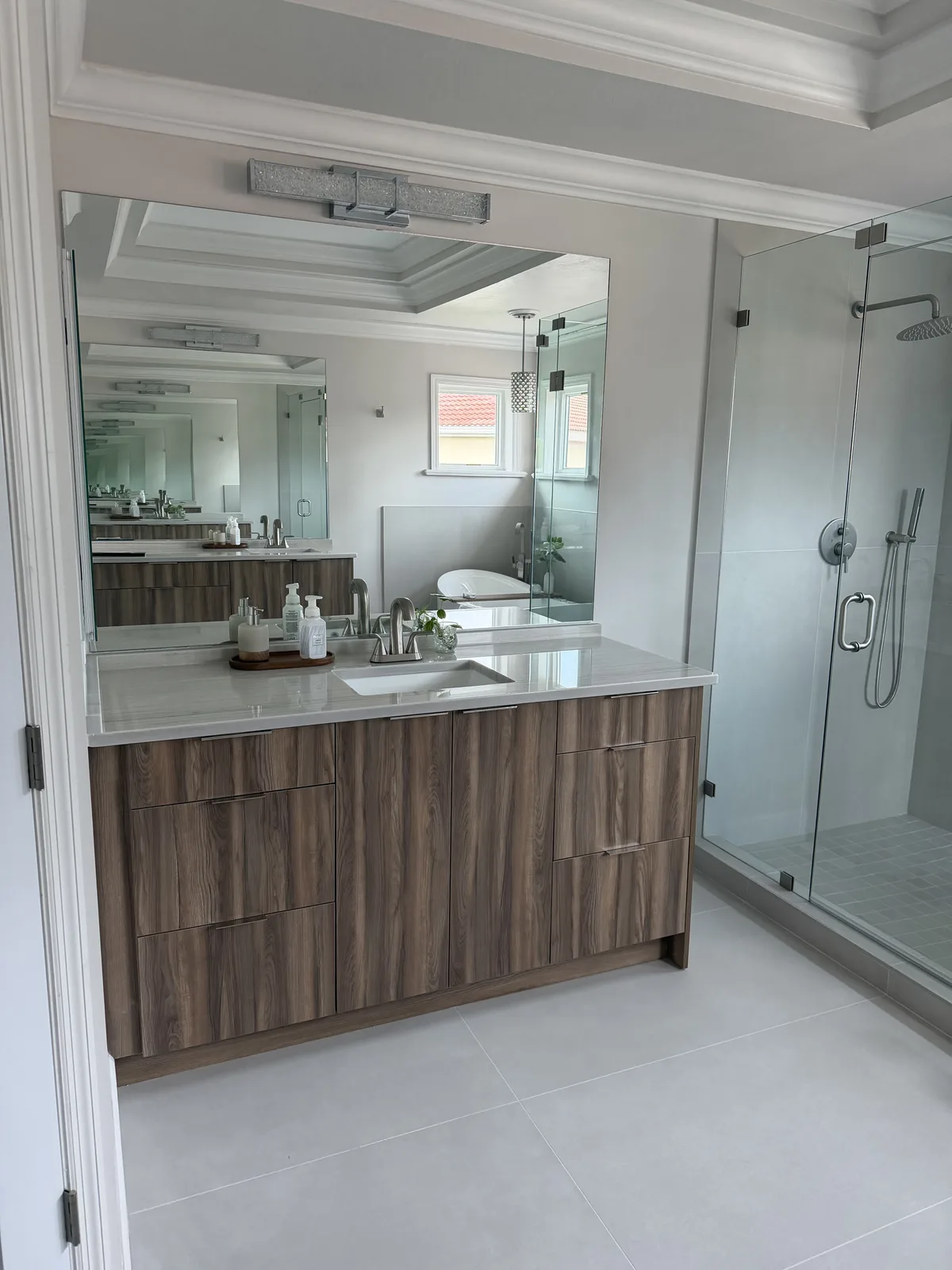 Walnut floating vanity beside a frameless glass walk-in shower, Fort Myers master bath