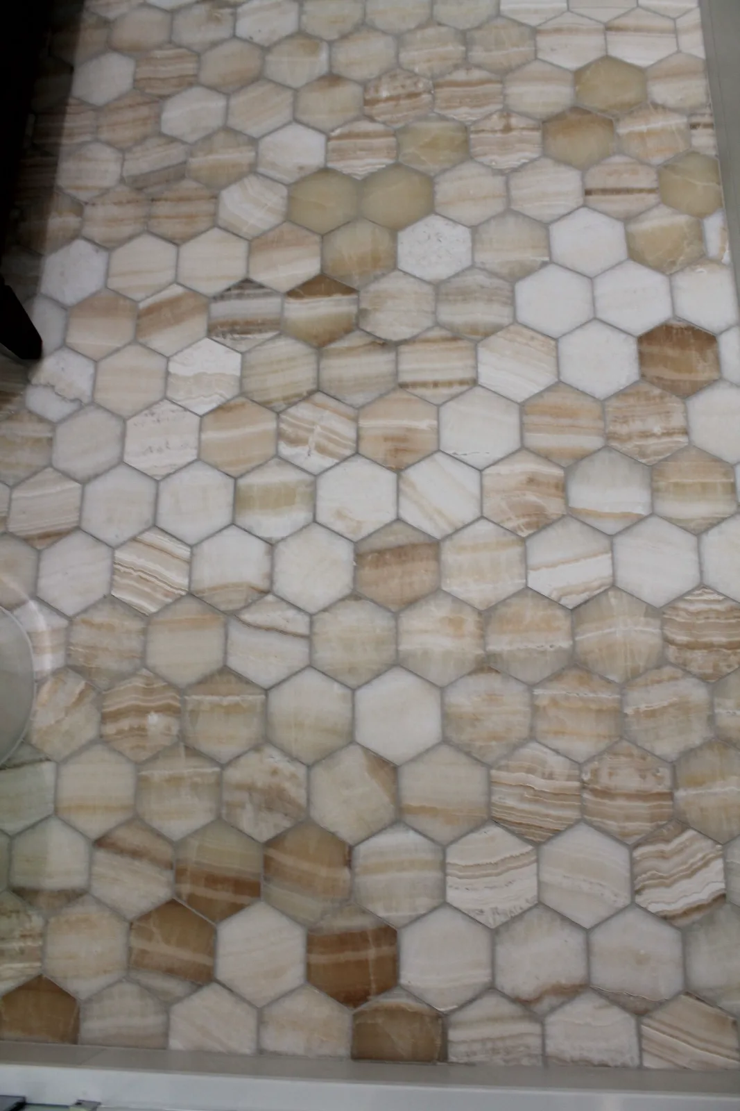 Close-up of beige onyx hexagon mosaic tile with tight grout joints