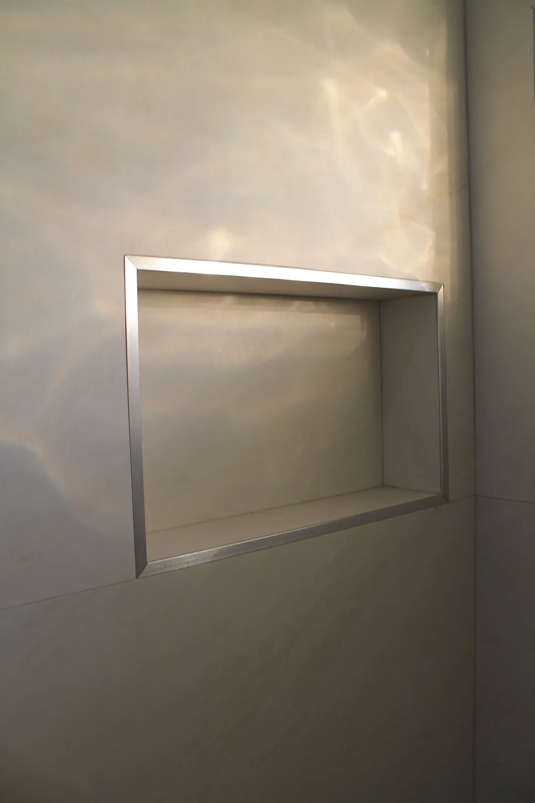 Recessed shower niche framed in polished chrome trim