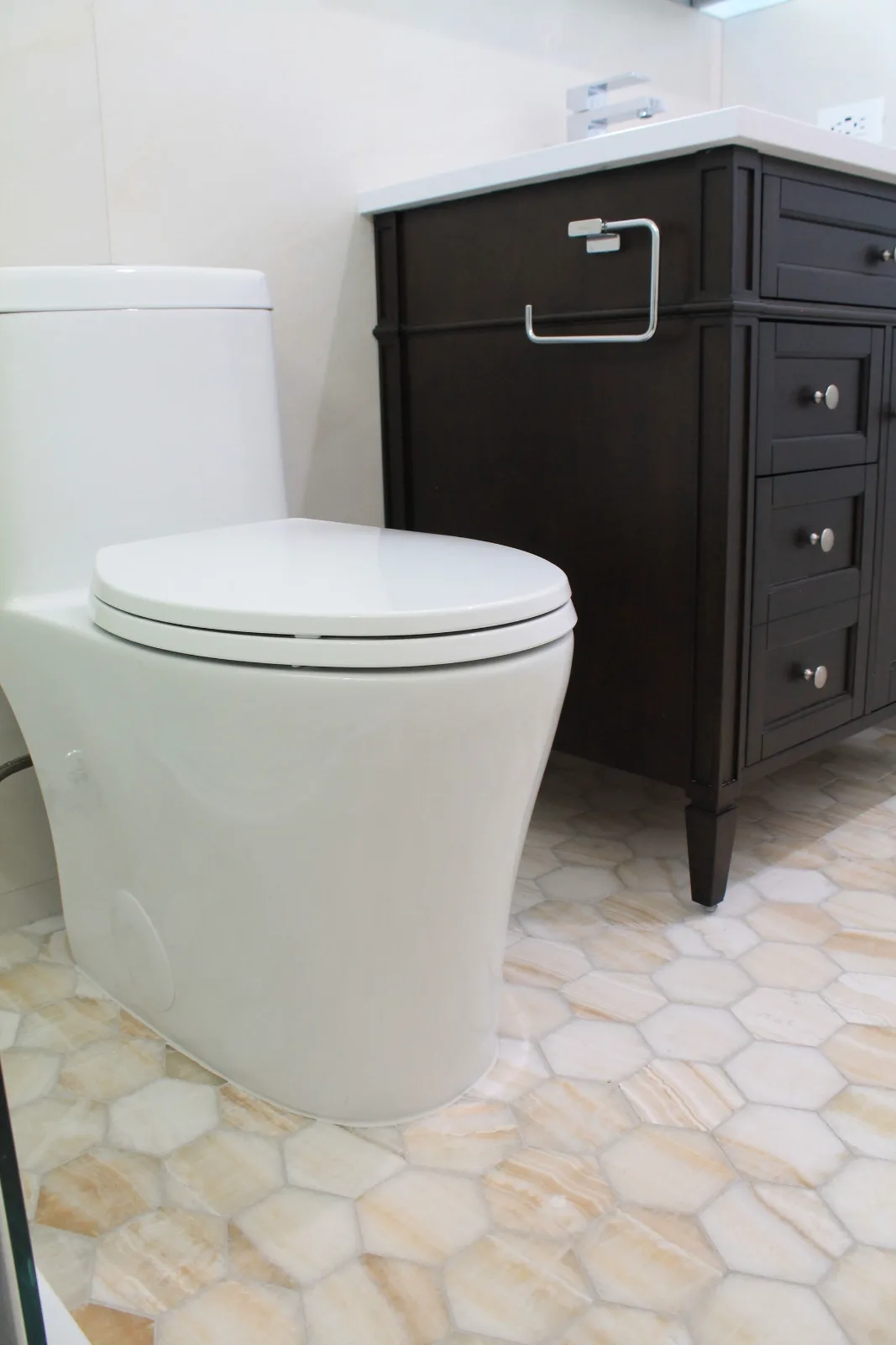 Comfort-height toilet beside an espresso vanity on hex mosaic tile