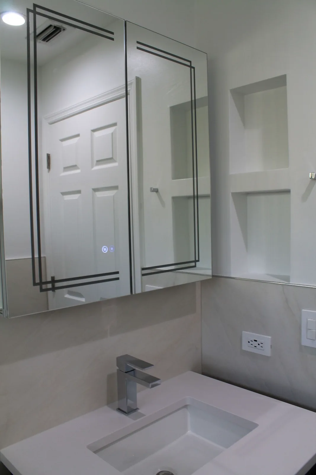 Mirrored LED medicine cabinet over a floating quartz vanity