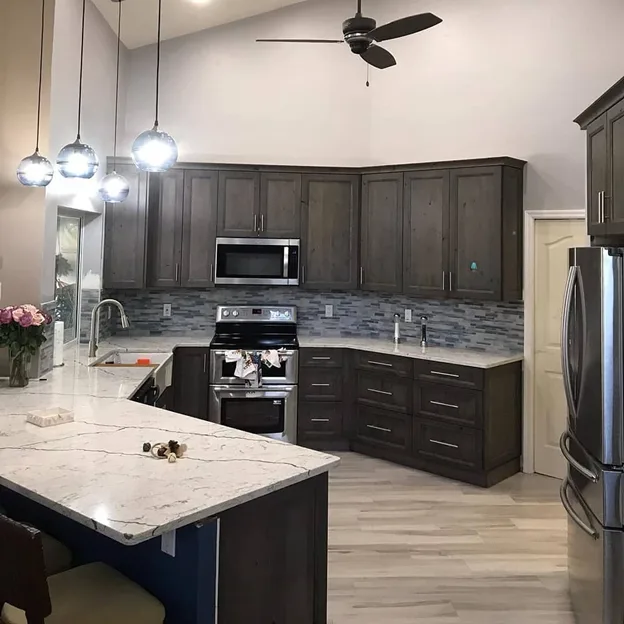 Dark stained wood kitchen with quartz peninsula and pendant lighting