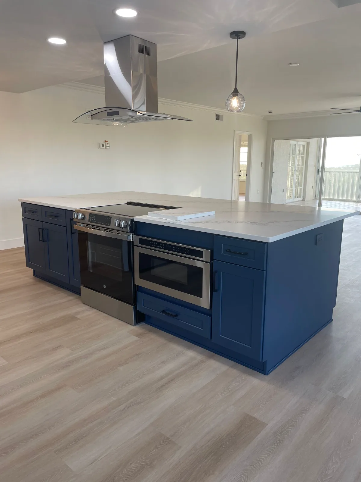 Navy kitchen island with quartz top, slide-in range, and stainless hood