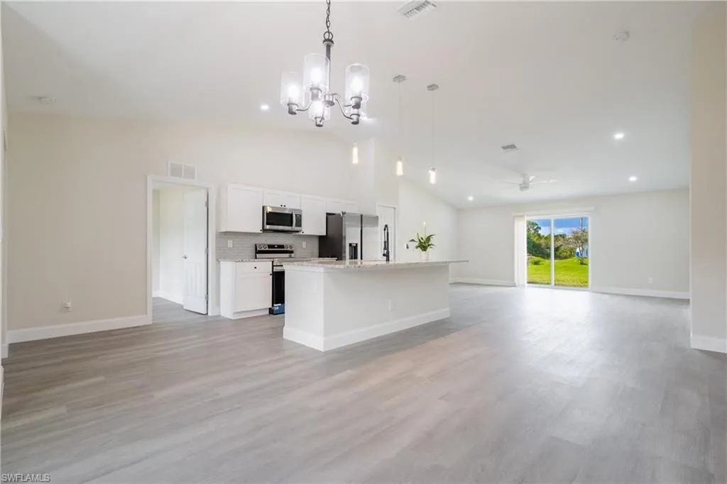 Open floor plan white kitchen with island and wide-plank vinyl flooring