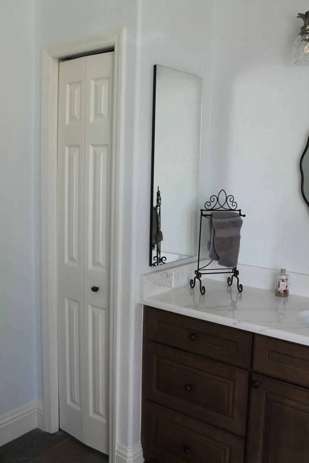 Remodeled master bath vanity wall with tall mirror and stained cabinetry
