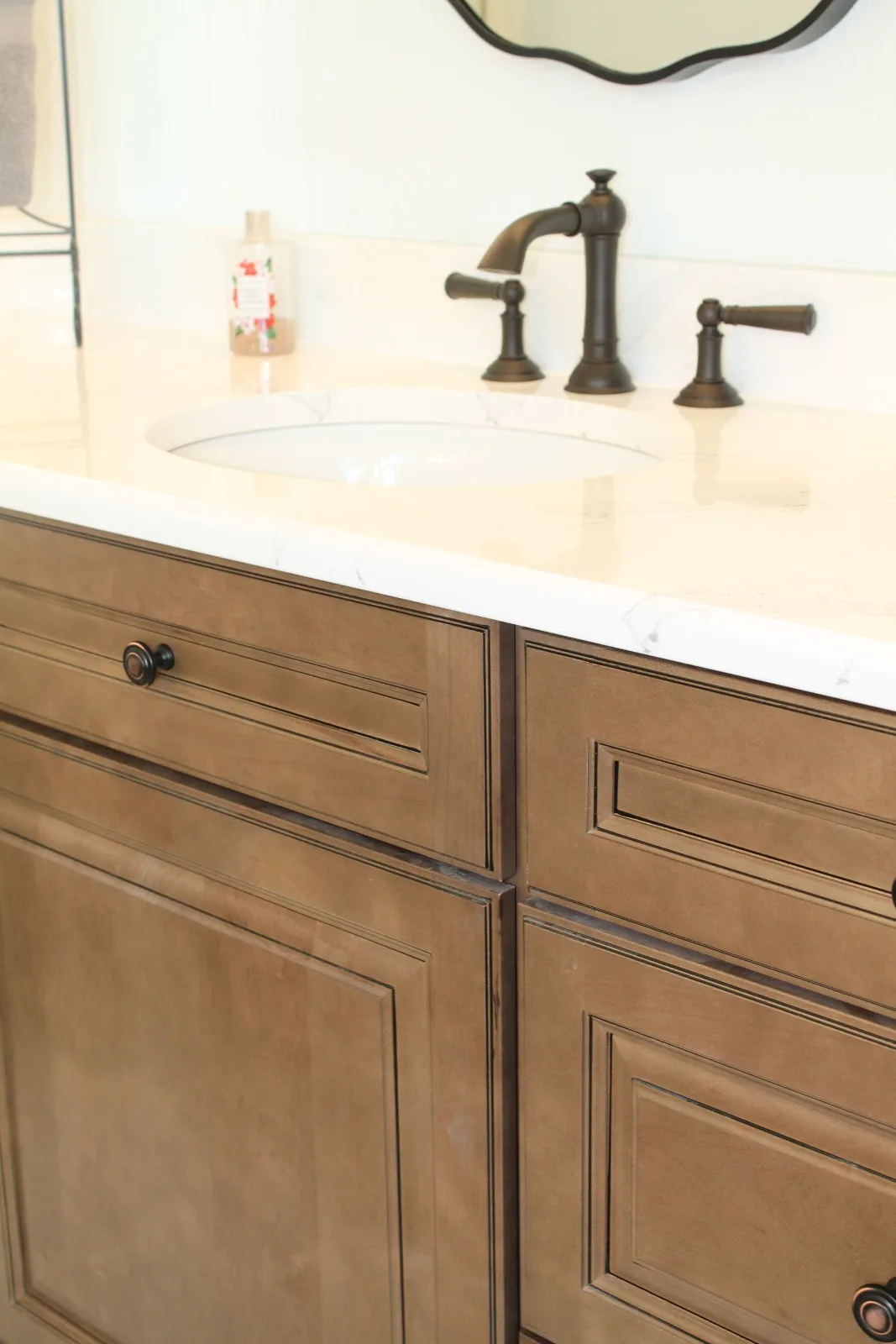 Quartz vanity top with bronze faucet over stained wood cabinets