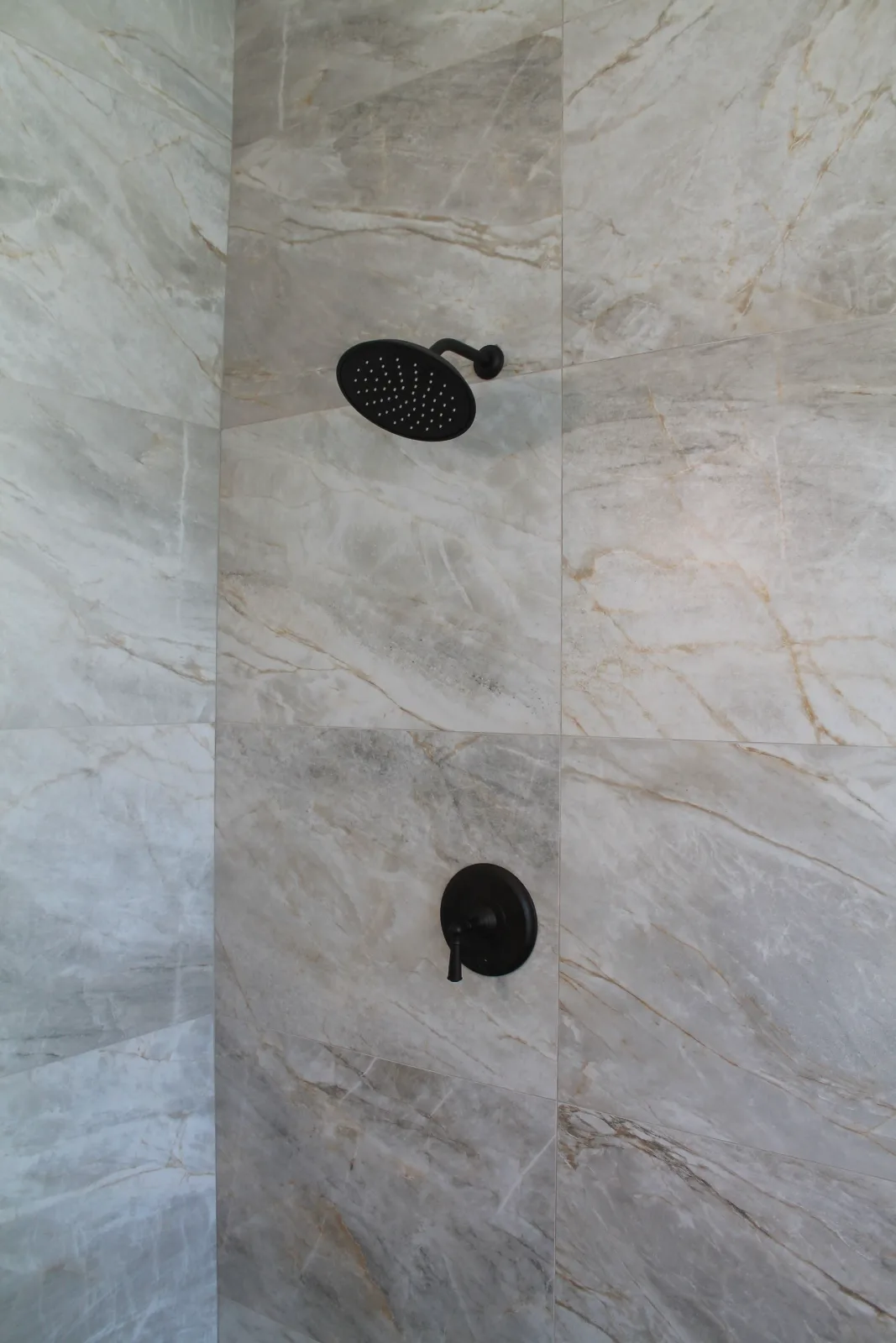 Quartzite-look porcelain shower wall with oil-rubbed bronze shower head and valve