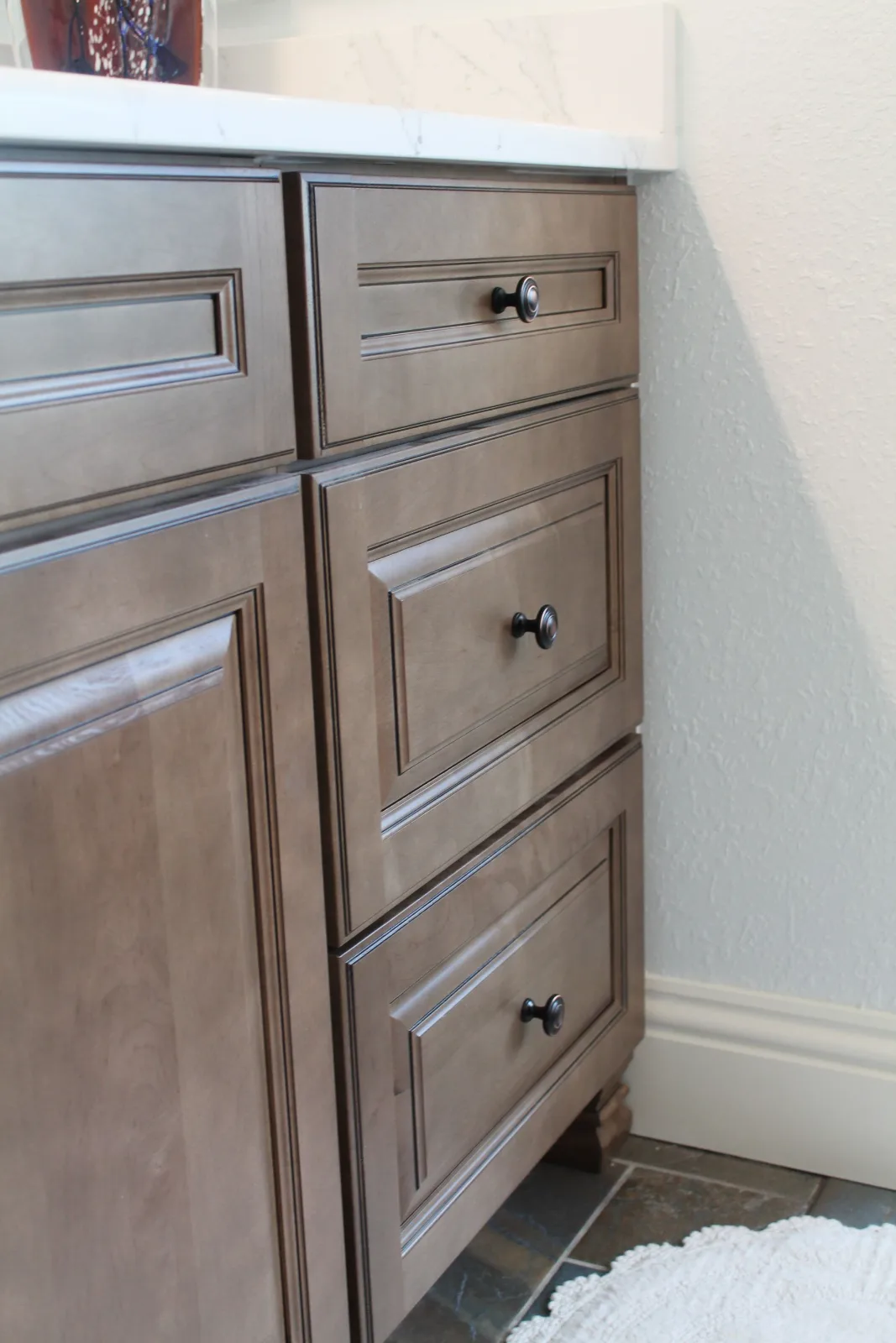 Stained wood vanity cabinet with raised-panel doors and oil-rubbed bronze knobs