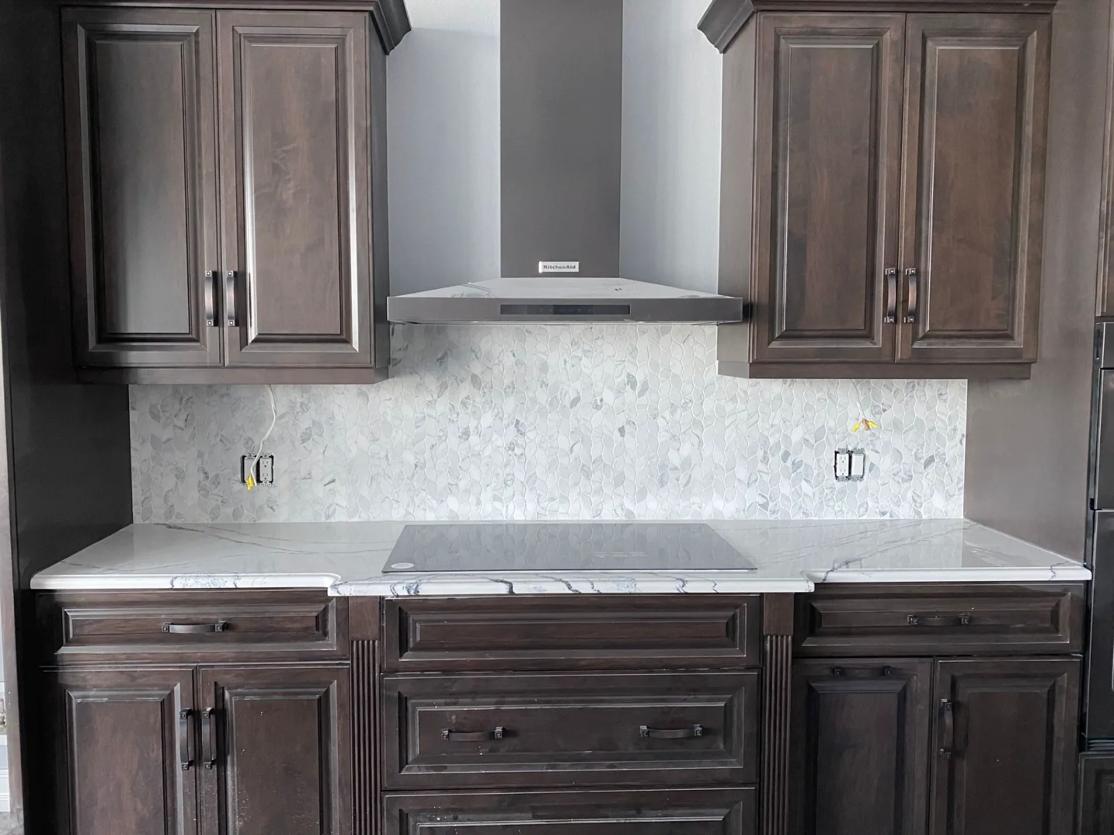 Espresso kitchen cabinets with a marble mosaic tile backsplash