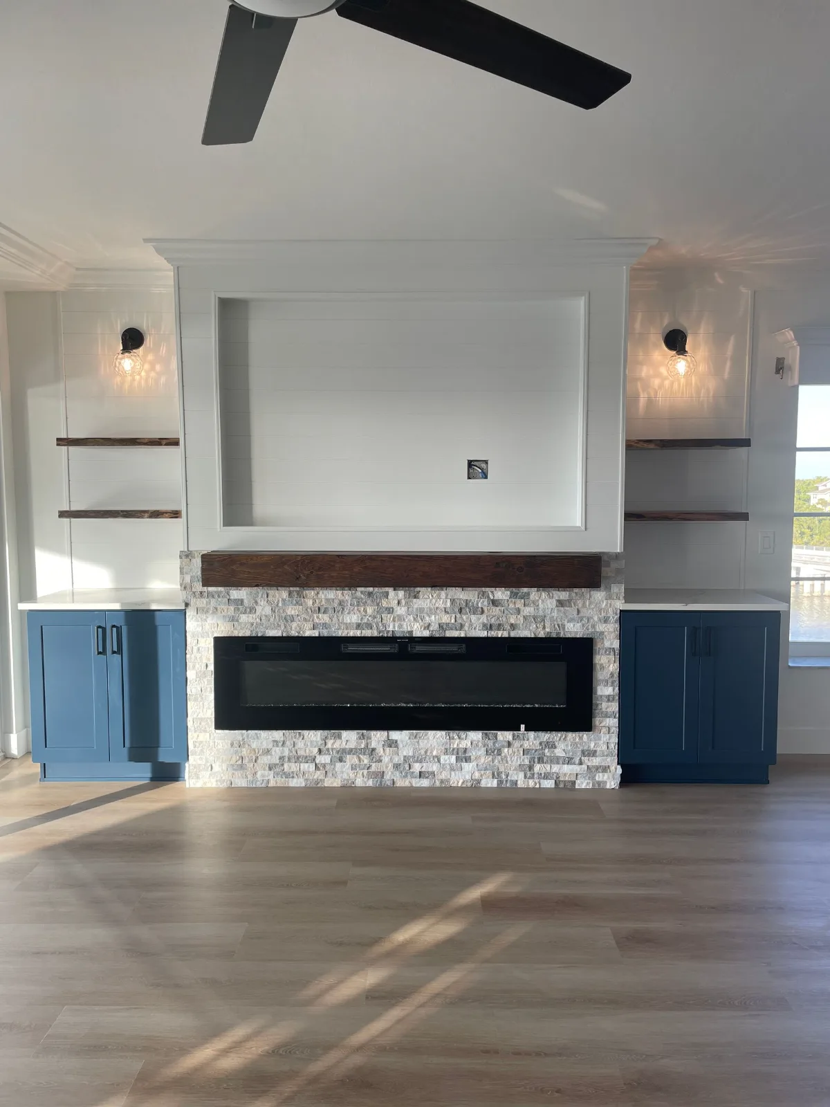 Stacked stone fireplace surround with a live-edge mantel, navy cabinetry and floating shelves