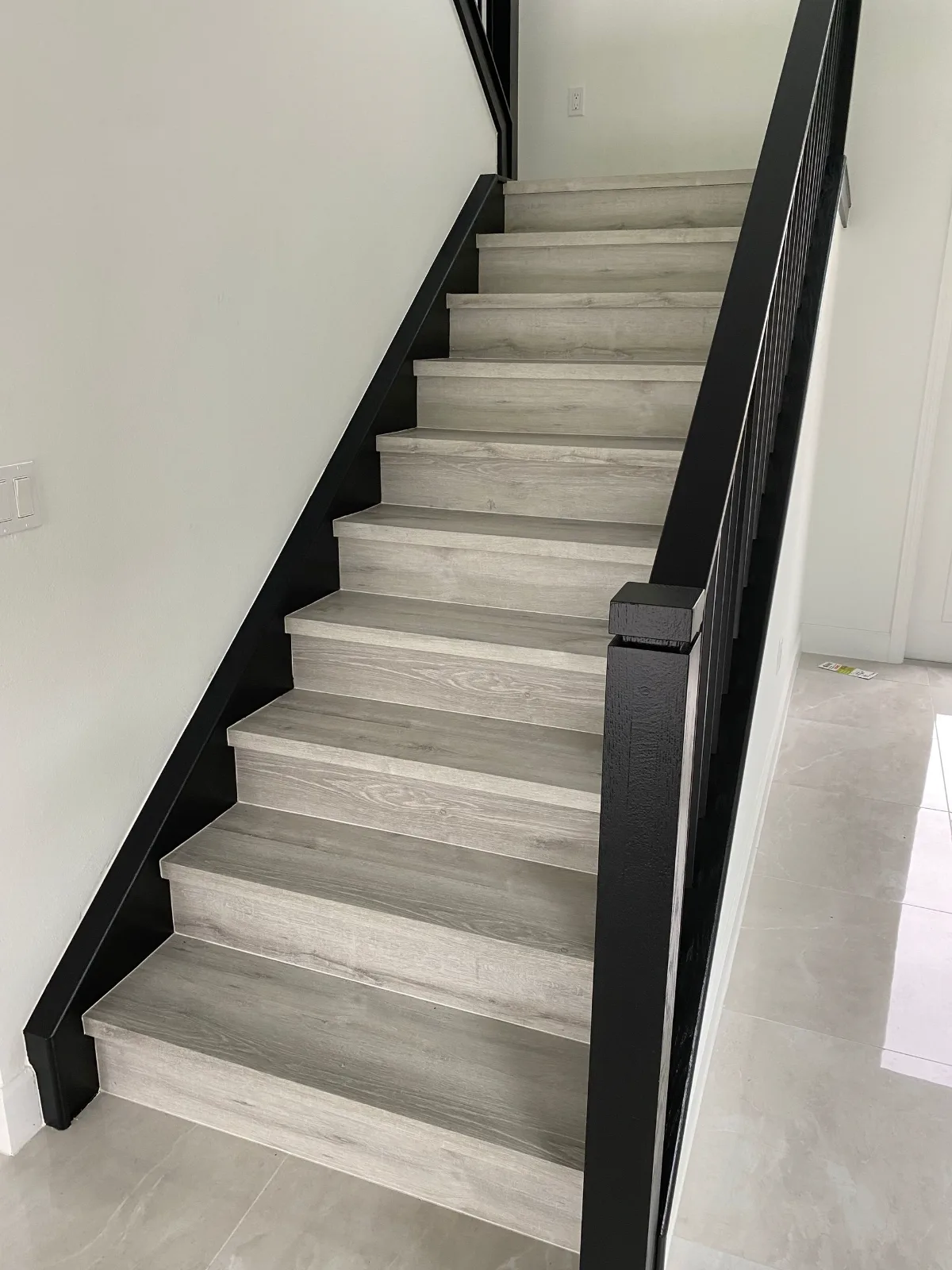 Gray LVP stair treads with a black metal railing and white risers