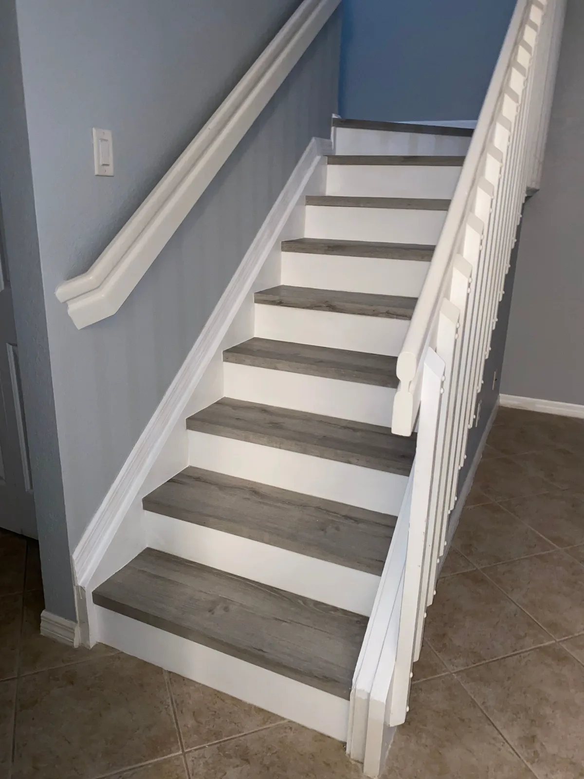 Luxury vinyl plank staircase with white vinyl risers and painted handrail
